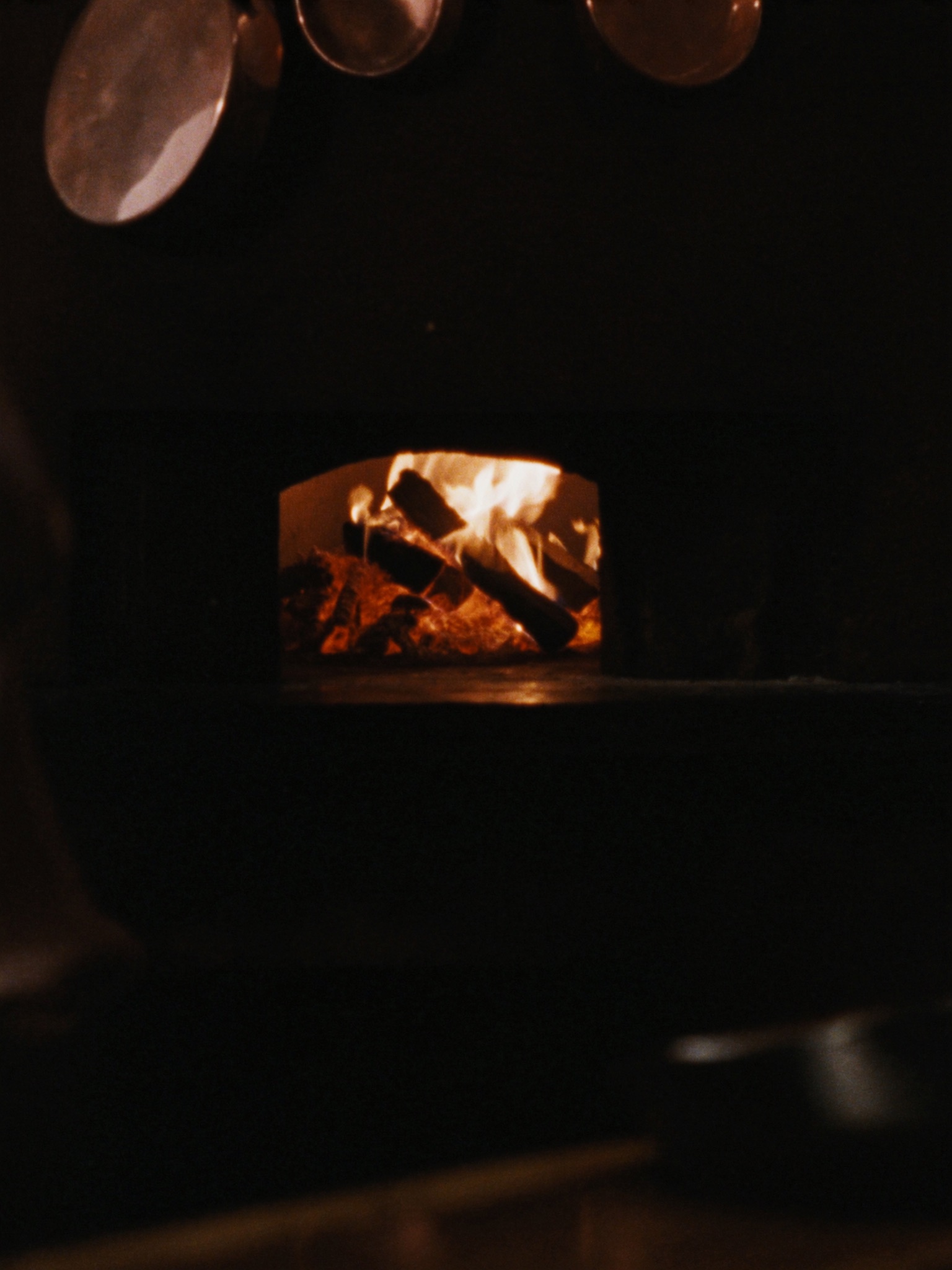 The wood-fired oven glowing in the open kitchen